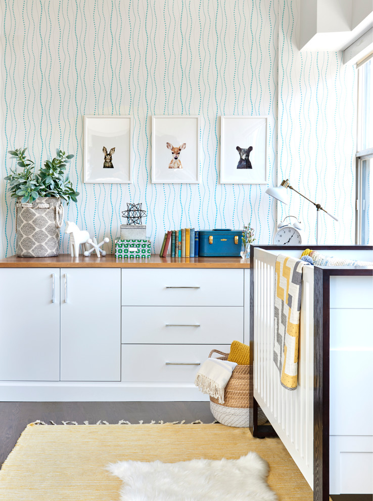 Esempio di una piccola cameretta per neonati neutra contemporanea con pareti blu e parquet chiaro