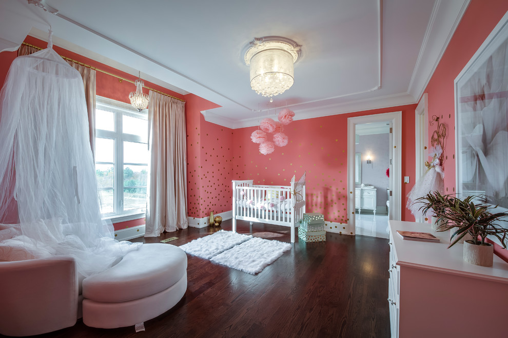 This is an example of a large traditional nursery for girls in Toronto with medium hardwood flooring, pink walls and brown floors.