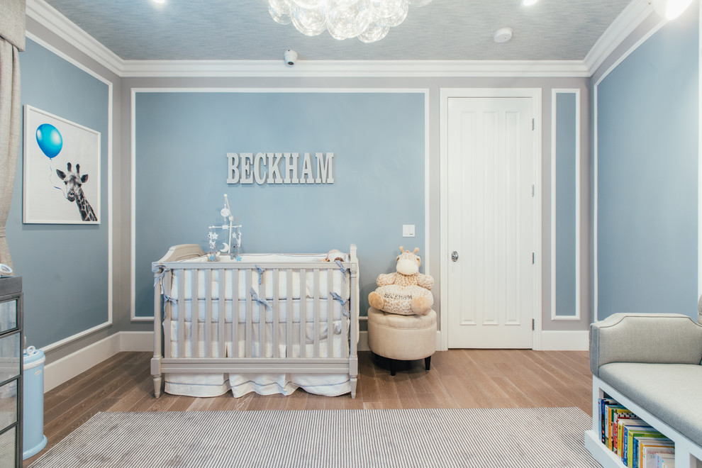 Diseño de habitación de bebé clásica con paredes azules, suelo de madera en tonos medios y suelo marrón