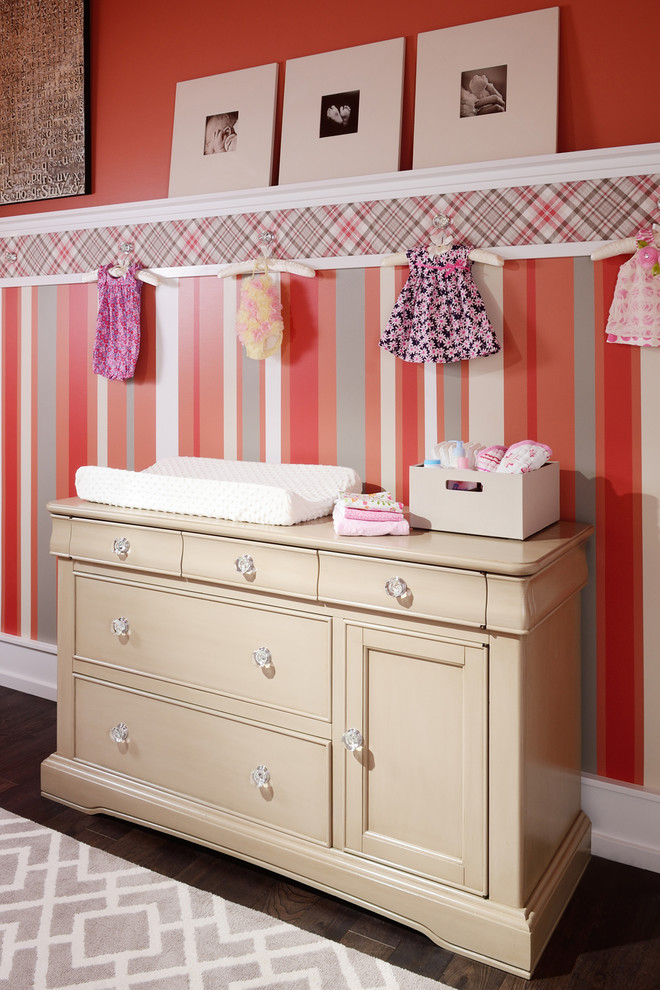 Medium sized traditional nursery for girls in Other with multi-coloured walls and medium hardwood flooring.