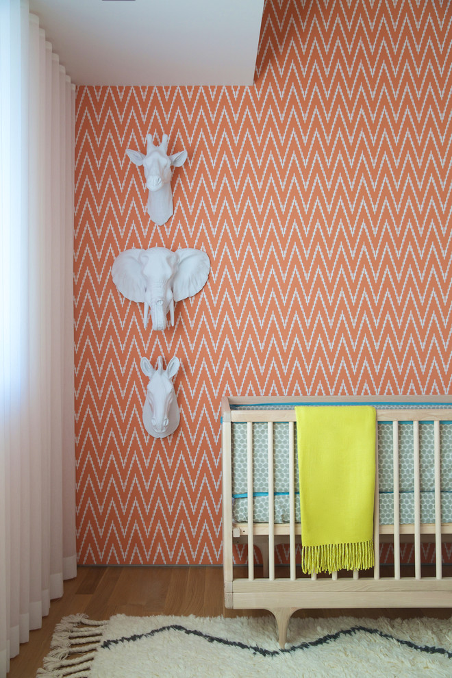 Foto di una cameretta per neonati minimalista con pareti multicolore e pavimento in legno massello medio