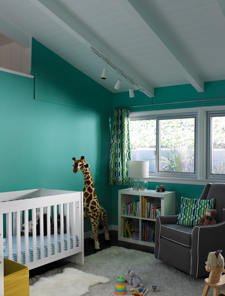 Ejemplo de habitación de bebé neutra retro con paredes azules y suelo de madera oscura