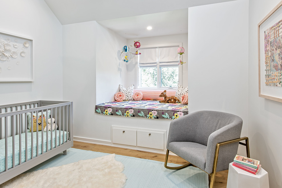Réalisation d'une chambre de bébé fille tradition avec un mur blanc, un sol en bois brun et un sol marron.