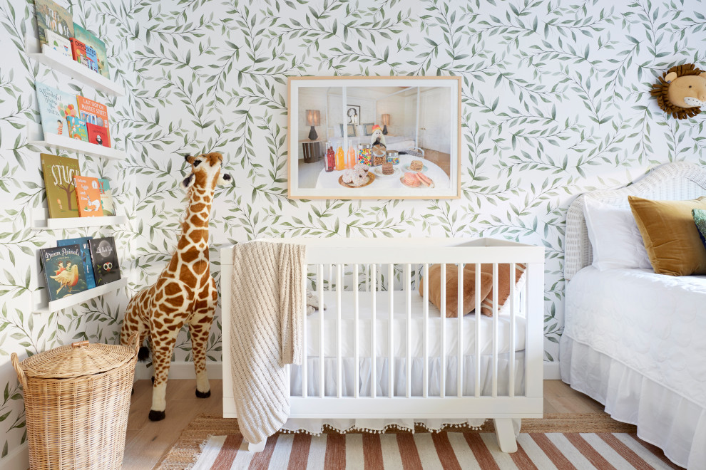This is an example of a bohemian gender neutral nursery in Los Angeles with multi-coloured walls, light hardwood flooring, brown floors and wallpapered walls.