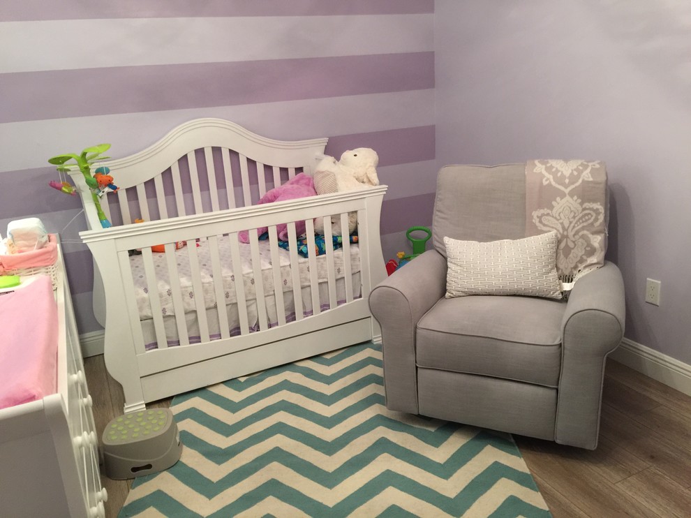 Imagen de habitación de bebé niña contemporánea de tamaño medio con paredes púrpuras, suelo de madera clara y suelo marrón