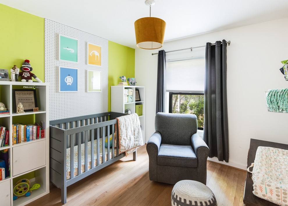 Modern gender neutral nursery in Denver with green walls, light hardwood flooring and a feature wall.