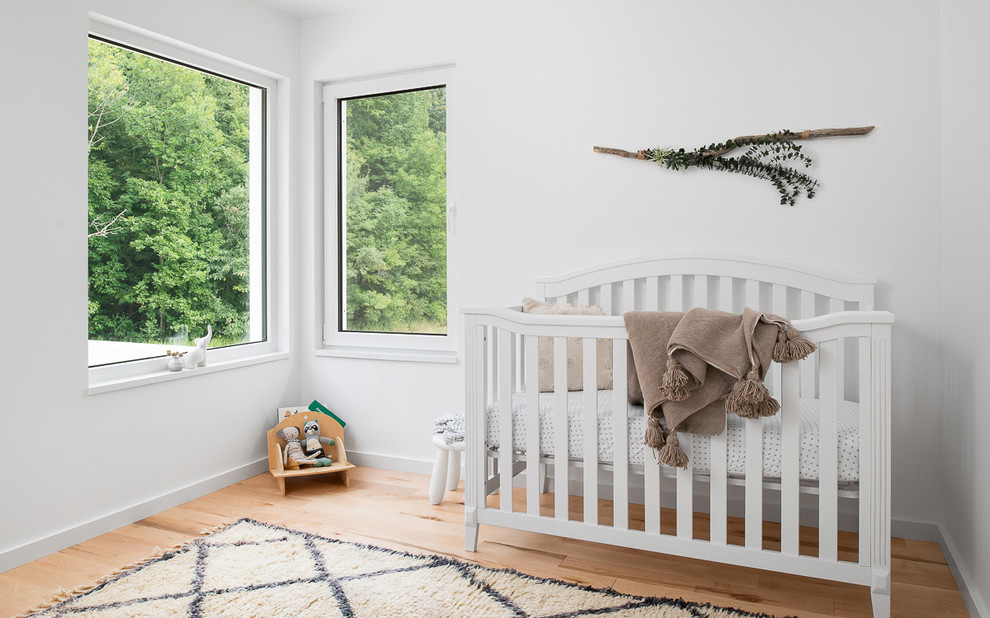 Aménagement d'une chambre de bébé neutre scandinave avec un mur blanc et parquet clair.