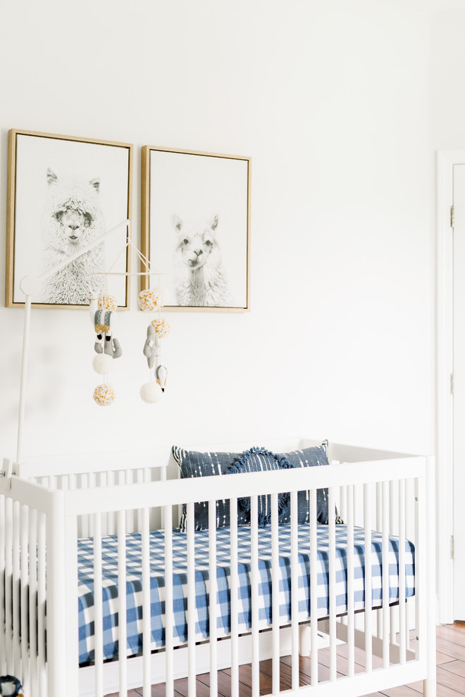 Réalisation d'une grande chambre de bébé garçon tradition avec un mur blanc, parquet foncé et un sol marron.