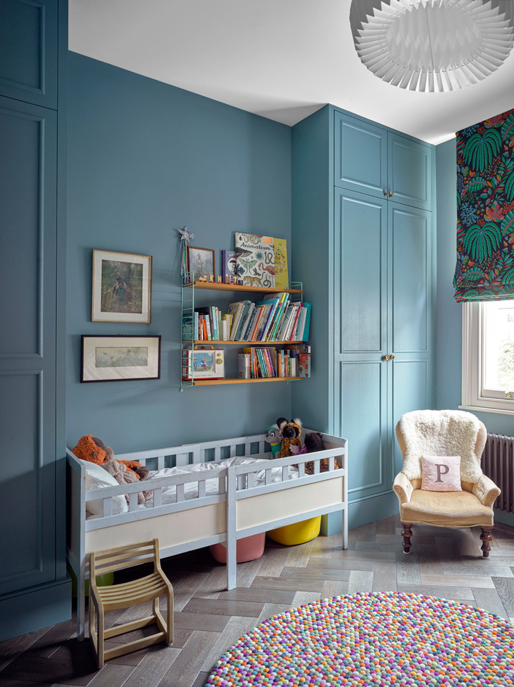 Idée de décoration pour une chambre de bébé neutre tradition de taille moyenne avec un mur bleu, parquet foncé et un sol marron.