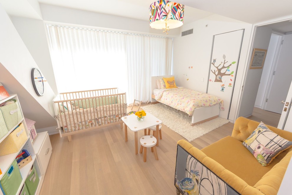 Ejemplo de habitación de bebé niña tradicional renovada de tamaño medio con paredes blancas y suelo de madera clara