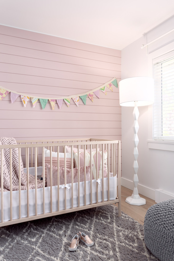 На фото: комната для малыша среднего размера в стиле кантри с розовыми стенами, светлым паркетным полом, бежевым полом и стенами из вагонки для девочки