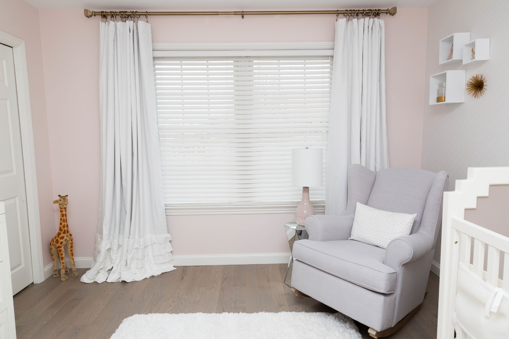 Aménagement d'une chambre de bébé fille moderne avec un mur rose et parquet clair.