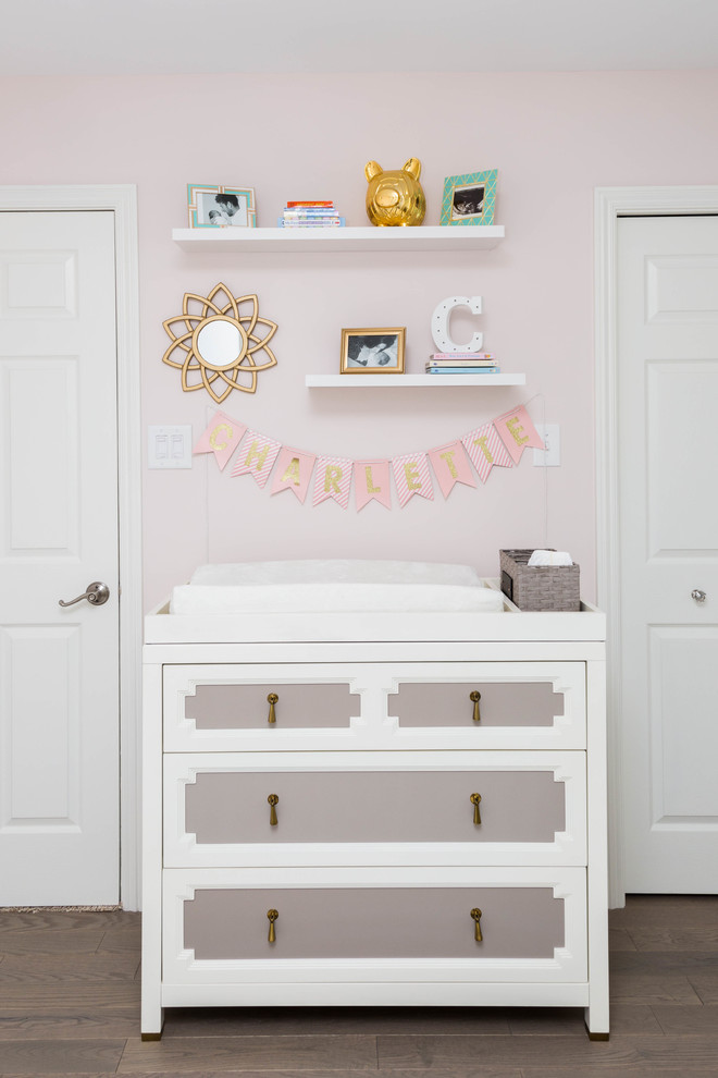 Design ideas for a modern nursery for girls in Philadelphia with pink walls and light hardwood flooring.