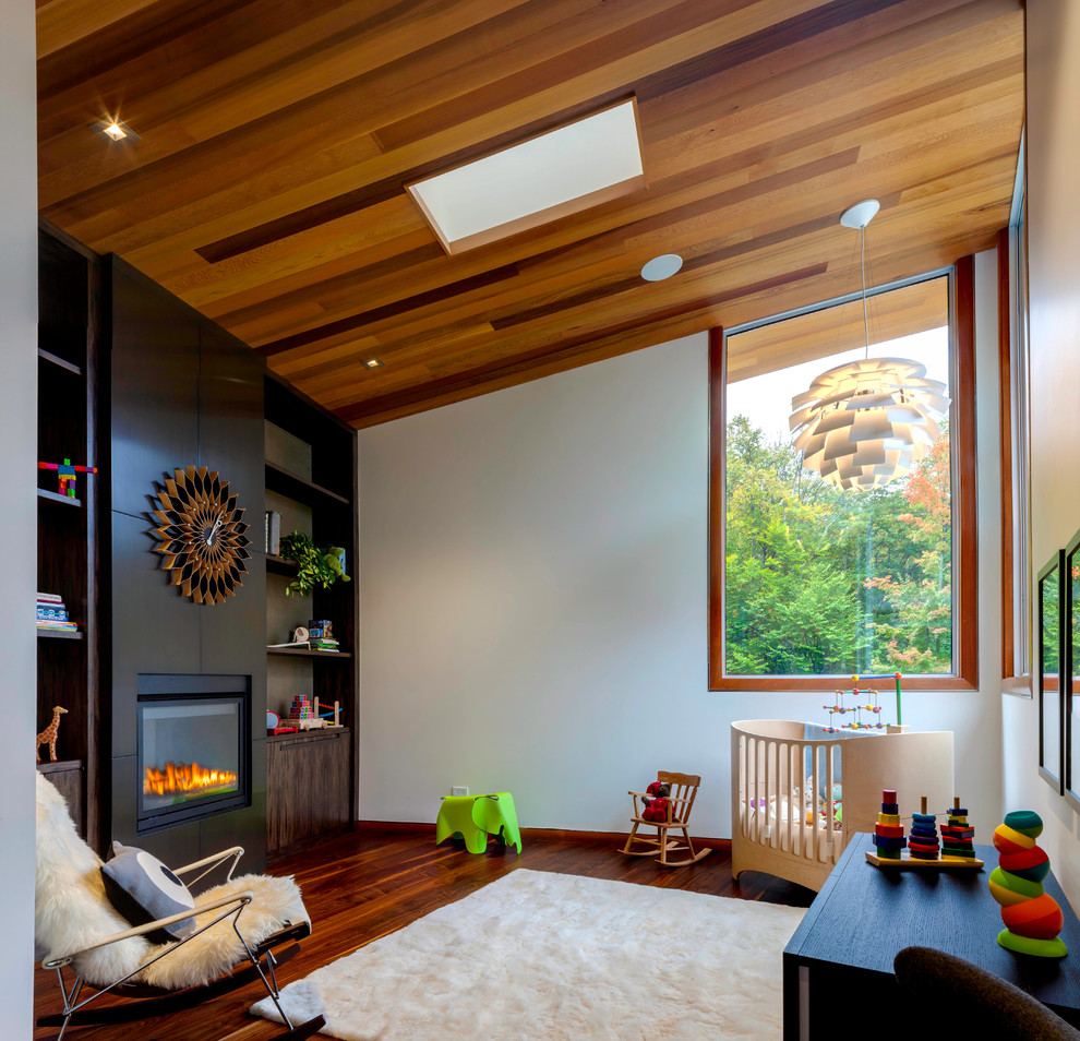 This is an example of a contemporary gender neutral nursery in Other with white walls, dark hardwood flooring, orange floors and a chimney breast.