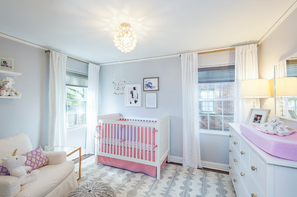 This is an example of a classic nursery for girls in Dallas with blue walls and dark hardwood flooring.