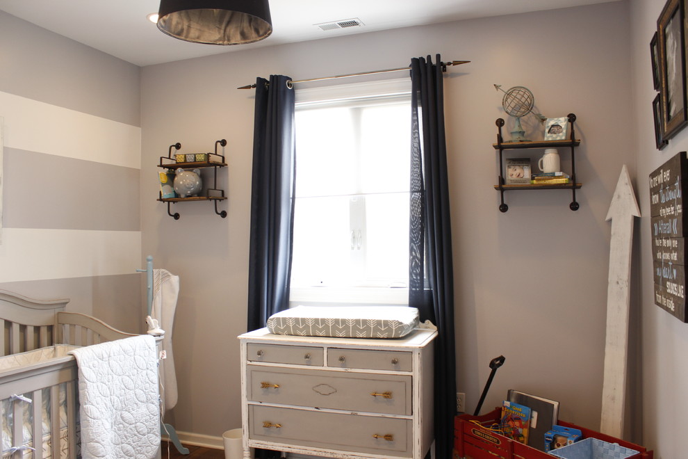 This is an example of a medium sized rustic nursery for boys in Chicago with grey walls and medium hardwood flooring.