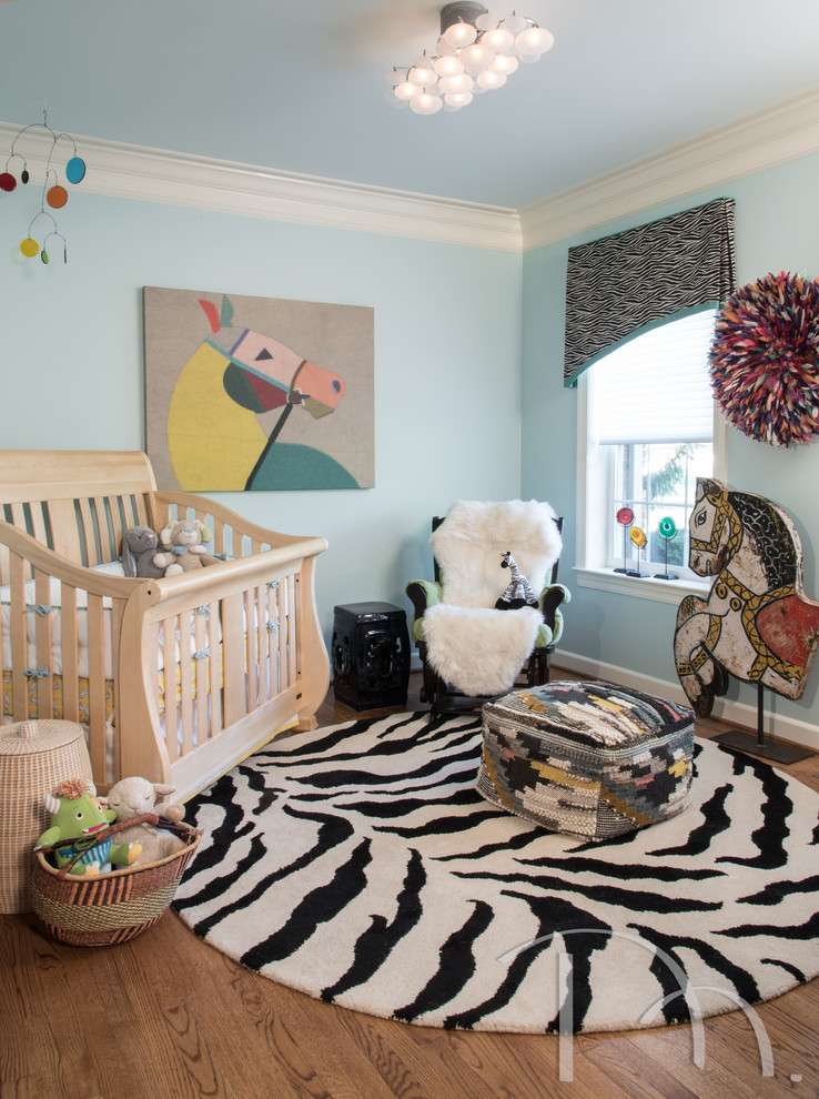 Réalisation d'une petite chambre de bébé garçon bohème avec un mur bleu et un sol en bois brun.