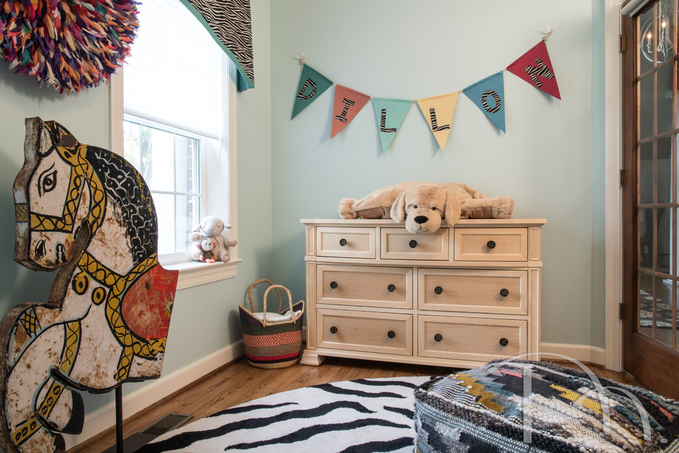 This is an example of a small eclectic nursery for boys with blue walls and medium hardwood flooring.