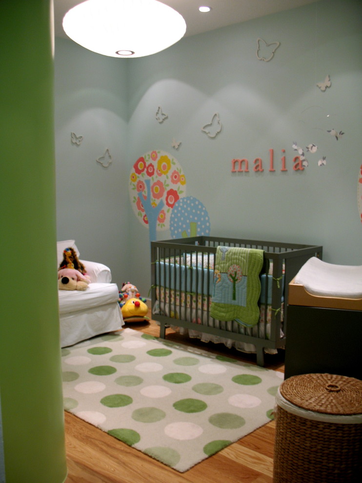 Ejemplo de habitación de bebé neutra contemporánea pequeña con paredes azules y suelo de madera clara