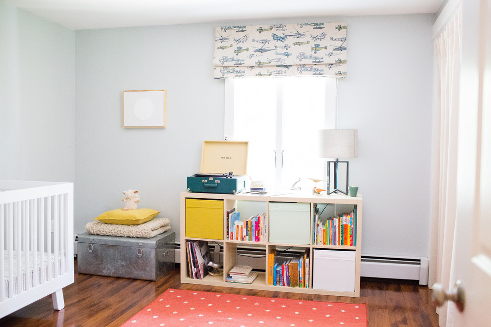 Modelo de habitación de bebé niño ecléctica pequeña con paredes azules y suelo de madera oscura