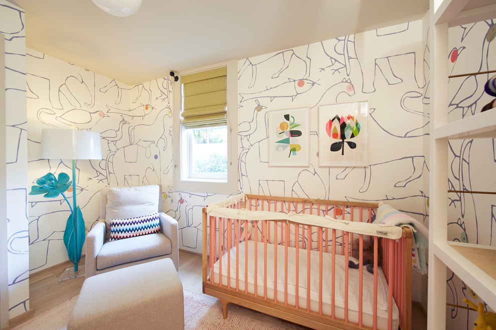 Exemple d'une petite chambre de bébé fille moderne avec un mur multicolore et parquet clair.