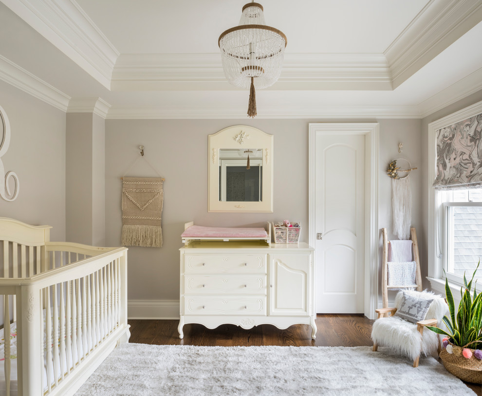 Cette photo montre une chambre de bébé neutre chic avec un mur beige, parquet foncé et un sol marron.