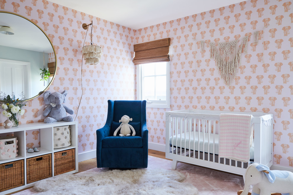 Example of a trendy girl medium tone wood floor and brown floor nursery design in Los Angeles with pink walls