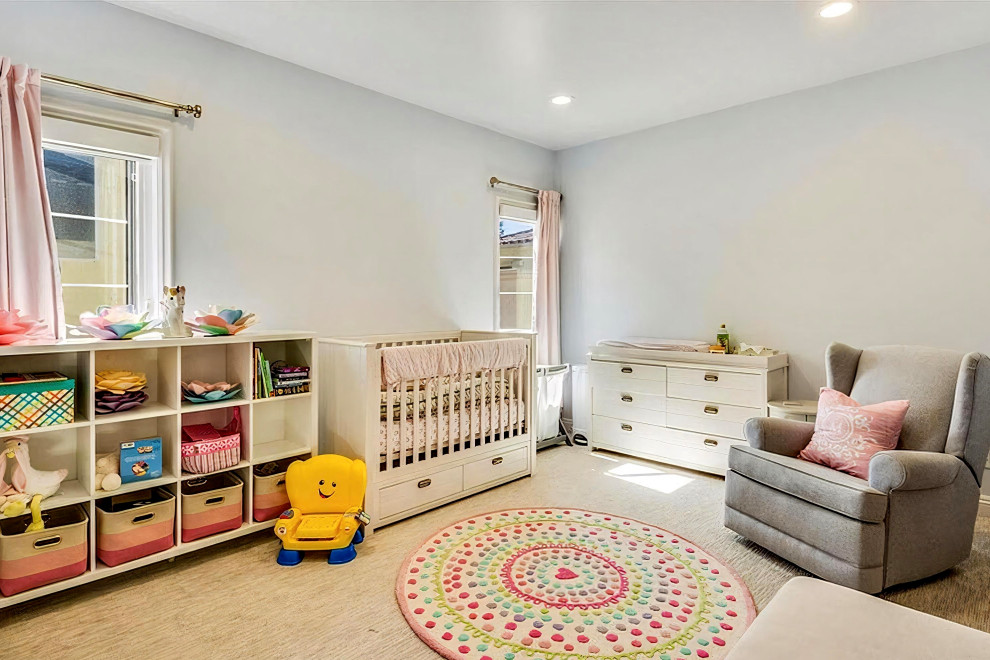 This is an example of a medium sized nursery for girls in Los Angeles with blue walls, carpet and beige floors.