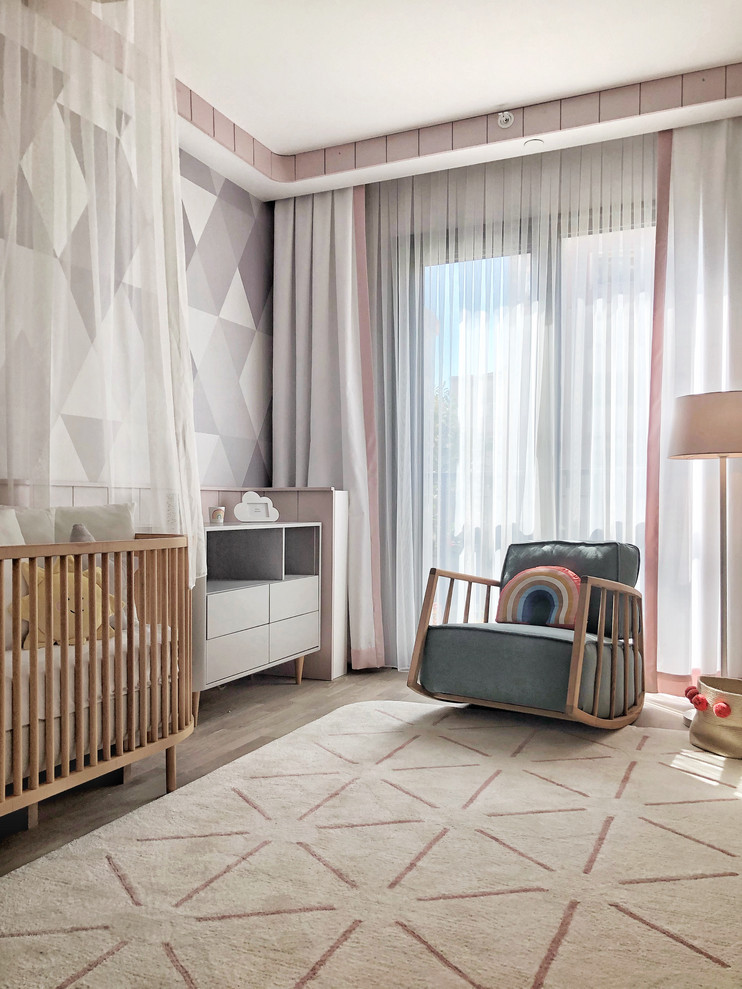 Ispirazione per una cameretta per neonata minimal di medie dimensioni con pavimento in laminato, pareti multicolore e carta da parati