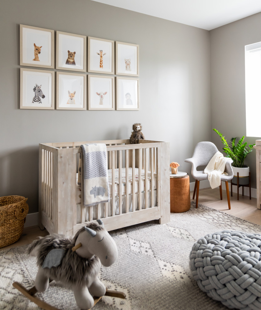 Diseño de habitación de bebé neutra marinera de tamaño medio con suelo beige, suelo de madera clara y paredes beige