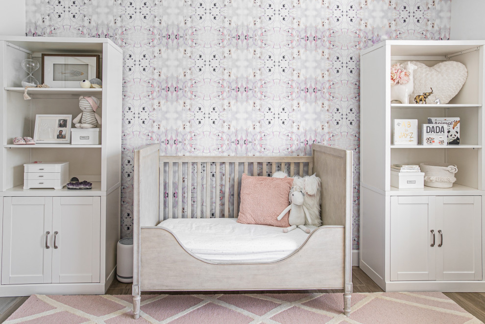 Modelo de habitación de bebé niña clásica renovada con paredes multicolor, suelo de madera en tonos medios, suelo marrón y papel pintado