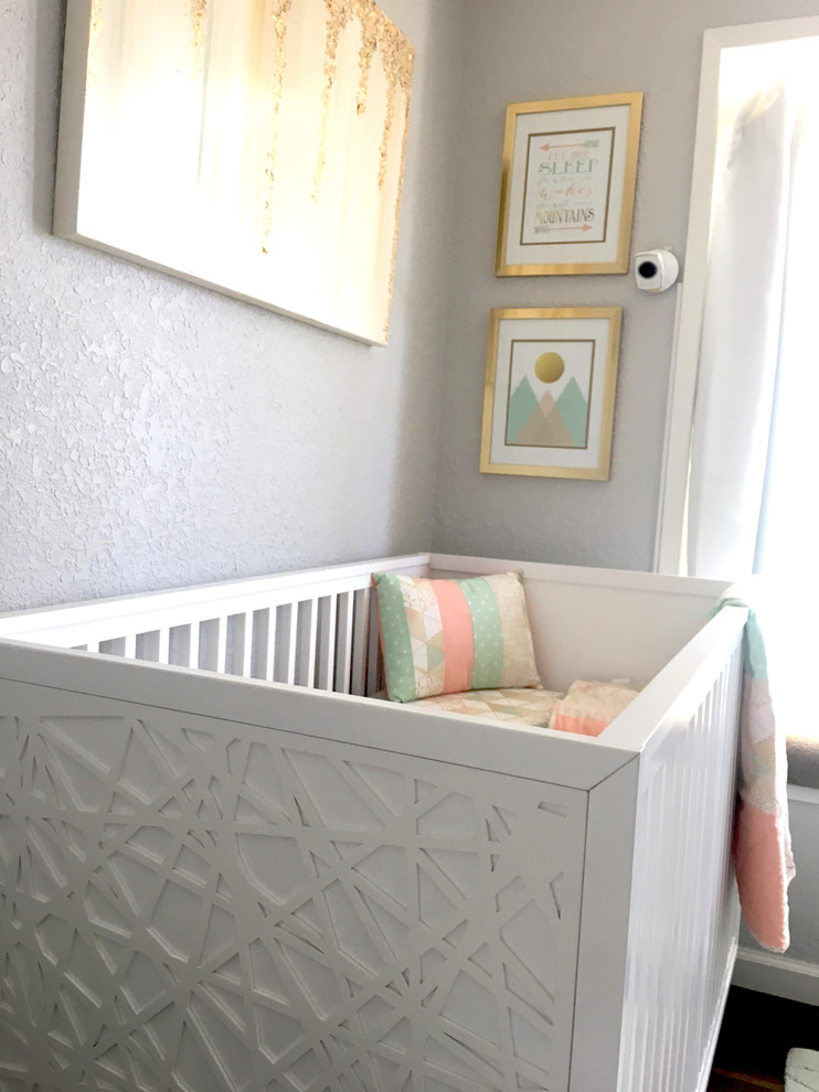 Ejemplo de habitación de bebé niña vintage pequeña con paredes grises, suelo de madera en tonos medios y suelo marrón