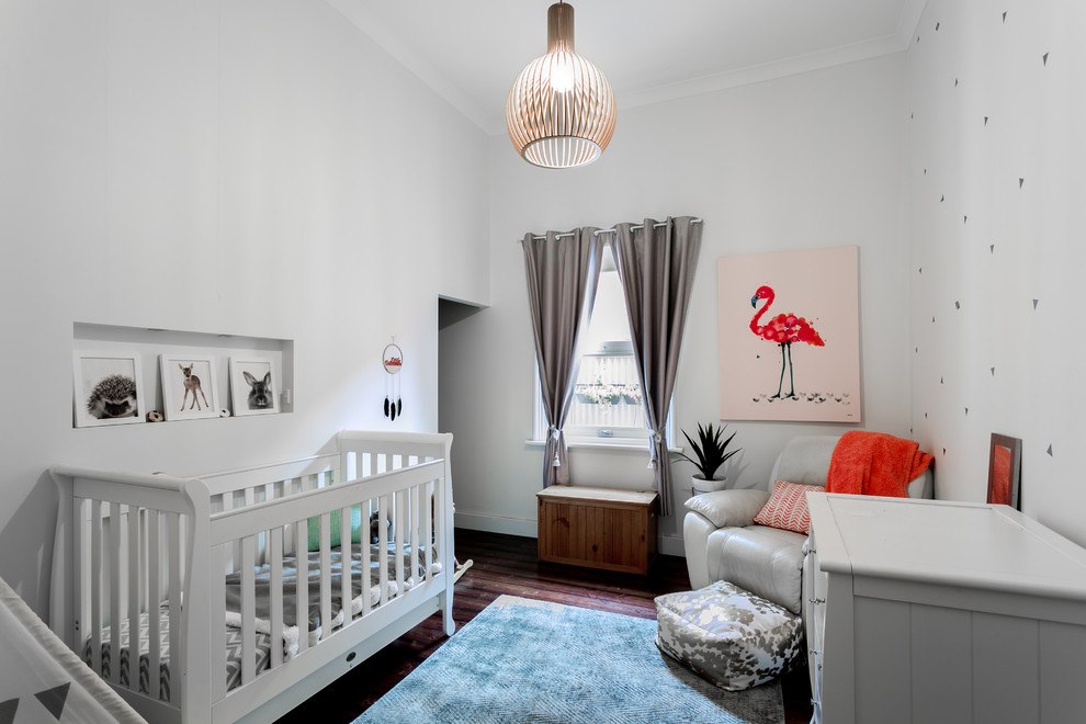 Ejemplo de habitación de bebé niña actual con paredes grises, suelo de madera oscura y suelo marrón