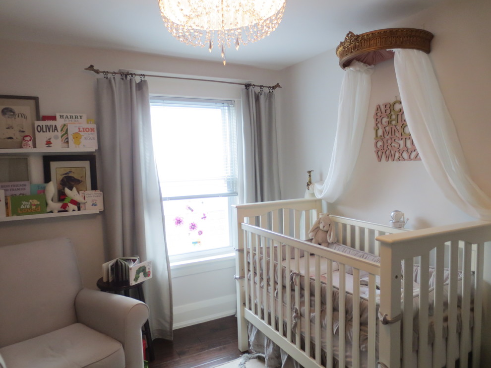 Réalisation d'une chambre de bébé fille tradition de taille moyenne avec un mur rose et parquet foncé.