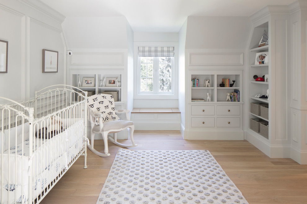 Réalisation d'une grande chambre de bébé neutre tradition avec un mur blanc, parquet clair et un sol marron.