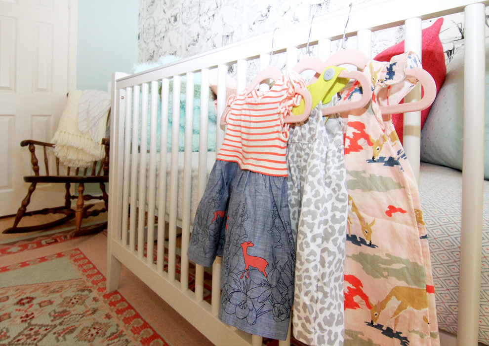 Diseño de habitación de bebé niña ecléctica grande con paredes azules y suelo de madera en tonos medios