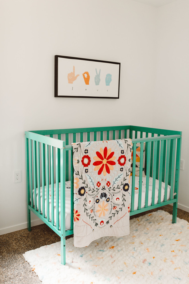 Diseño de habitación de bebé neutra moderna con paredes blancas, suelo de cemento y suelo marrón