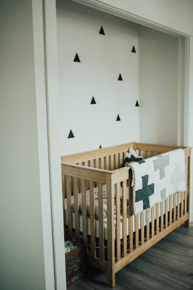 This is an example of a medium sized scandinavian gender neutral nursery in Vancouver with white walls and vinyl flooring.