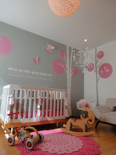 This is an example of a modern nursery for girls in Miami with grey walls and medium hardwood flooring.