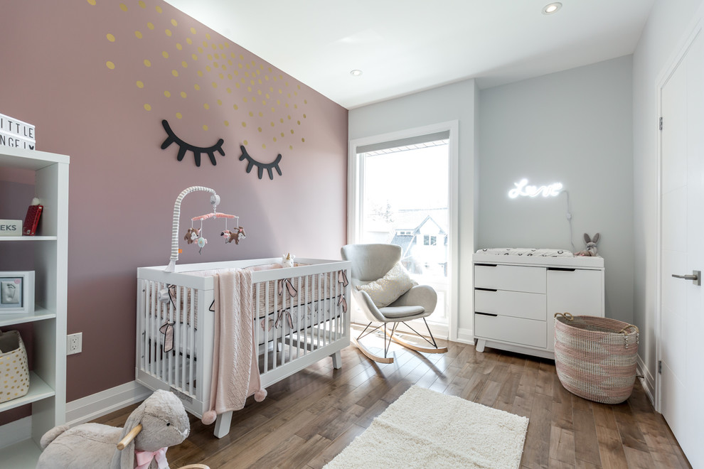 Cette photo montre une chambre de bébé fille tendance avec un mur violet et un sol en bois brun.