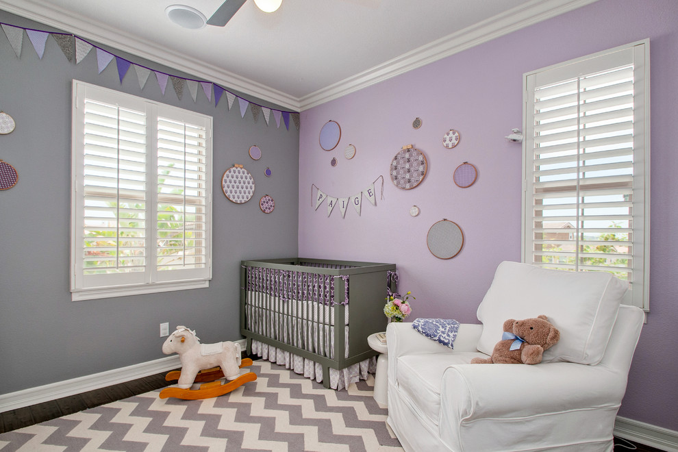 Exemple d'une chambre de bébé fille chic de taille moyenne avec un mur violet et parquet foncé.
