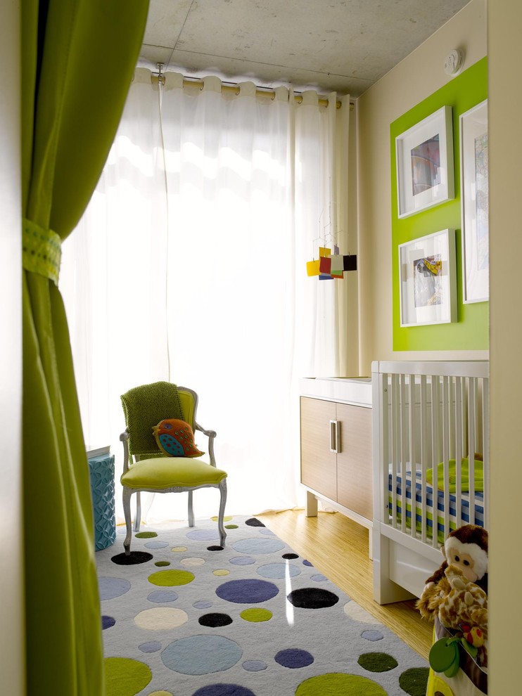 Immagine di una piccola cameretta per neonati neutra minimal con pareti verdi e pavimento in bambù