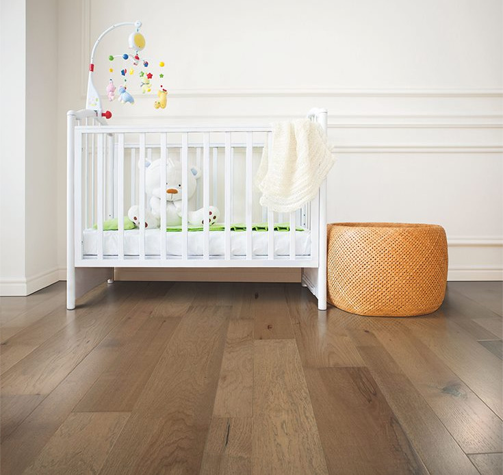 Idée de décoration pour une chambre de bébé fille nordique de taille moyenne avec un mur blanc et un sol en bois brun.