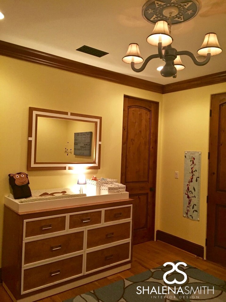 Ejemplo de habitación de bebé neutra contemporánea con paredes amarillas y suelo de madera en tonos medios