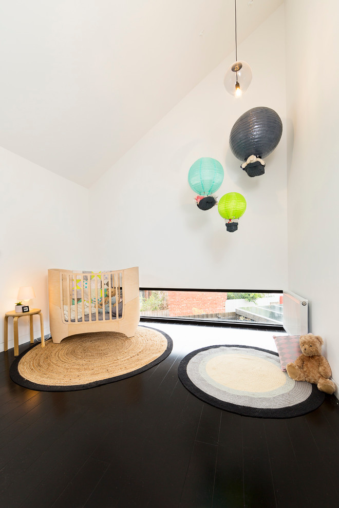Стильный дизайн: нейтральная комната для малыша среднего размера в современном стиле с белыми стенами, темным паркетным полом и черным полом - последний тренд