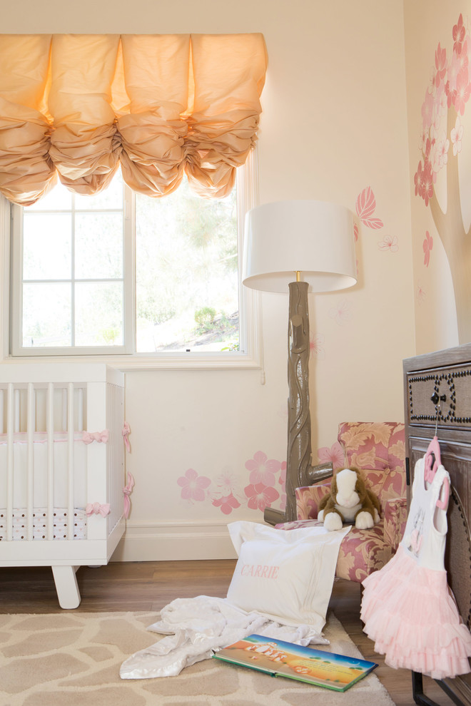 Example of a large tuscan light wood floor nursery design in San Diego with white walls