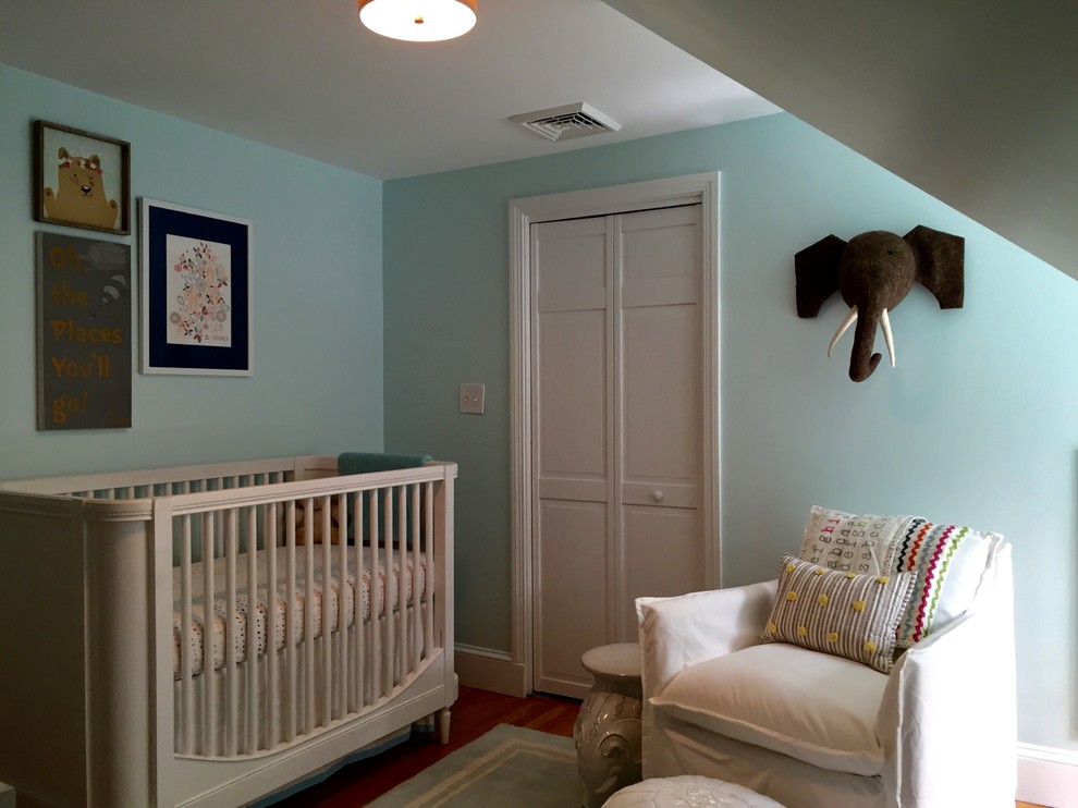 Modelo de habitación de bebé neutra minimalista de tamaño medio con paredes azules, suelo de madera en tonos medios y suelo marrón