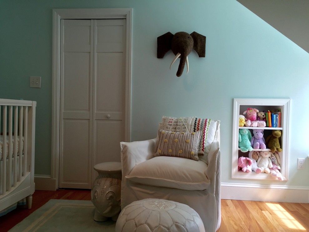 Ejemplo de habitación de bebé neutra minimalista de tamaño medio con paredes azules y suelo de madera en tonos medios