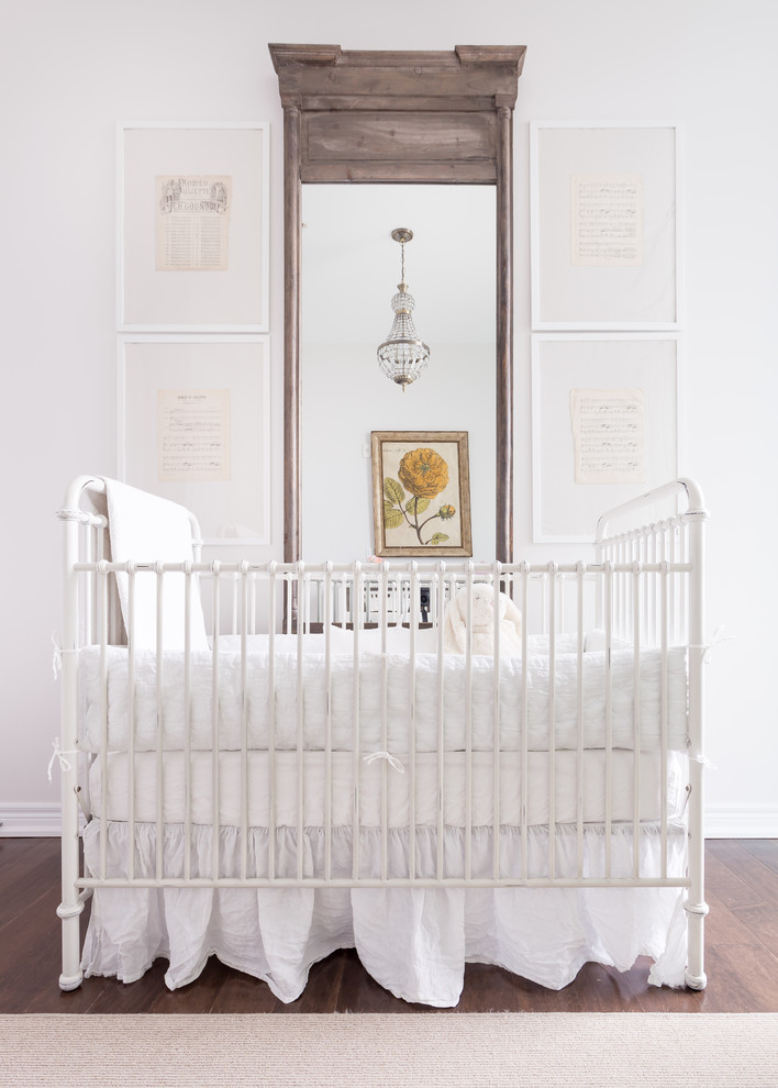 Ejemplo de habitación de bebé niña tradicional renovada grande con paredes blancas, suelo de madera oscura y suelo marrón