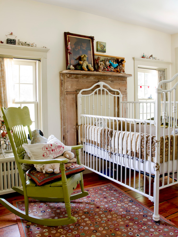 Diseño de habitación de bebé neutra ecléctica con paredes blancas y suelo de madera en tonos medios